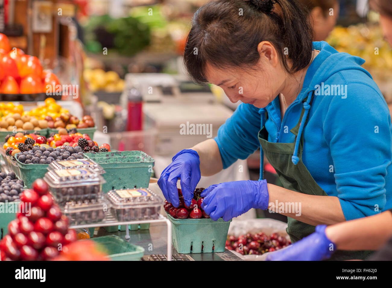 Vendor creating fruit stand display at Granville Island Farmers Market, Vancouver City, British Columbia. Stock Photo
