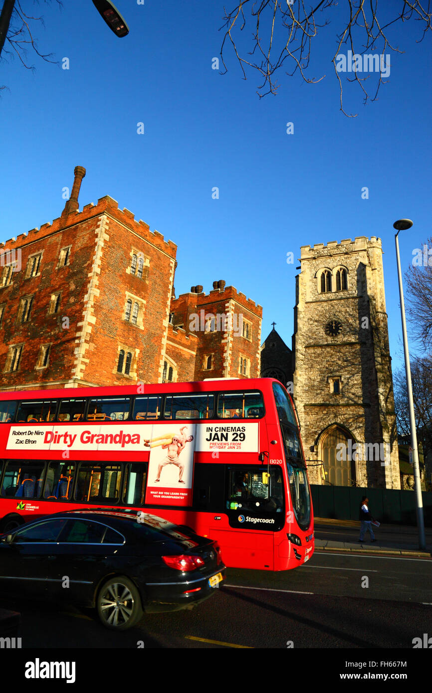 Red double decker bus advertising Dirty Grandpa passing Morton's Tower, part of Lambeth Palace, London, England Stock Photo