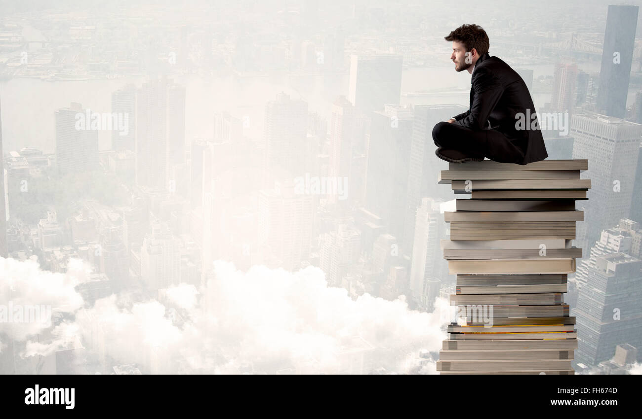 Student in city sitting on stack of books Stock Photo - Alamy