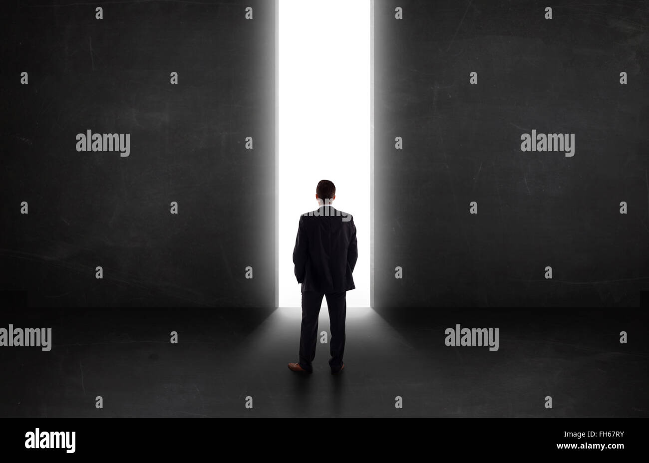 Business person looking at wall with light tunnel opening Stock Photo