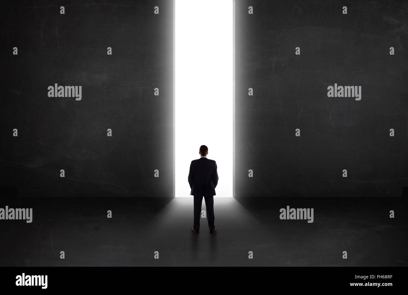 Business person looking at wall with light tunnel opening Stock Photo