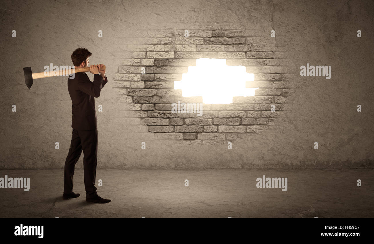Business man hitting brick wall with hammer and opening a hole Stock Photo Alamy