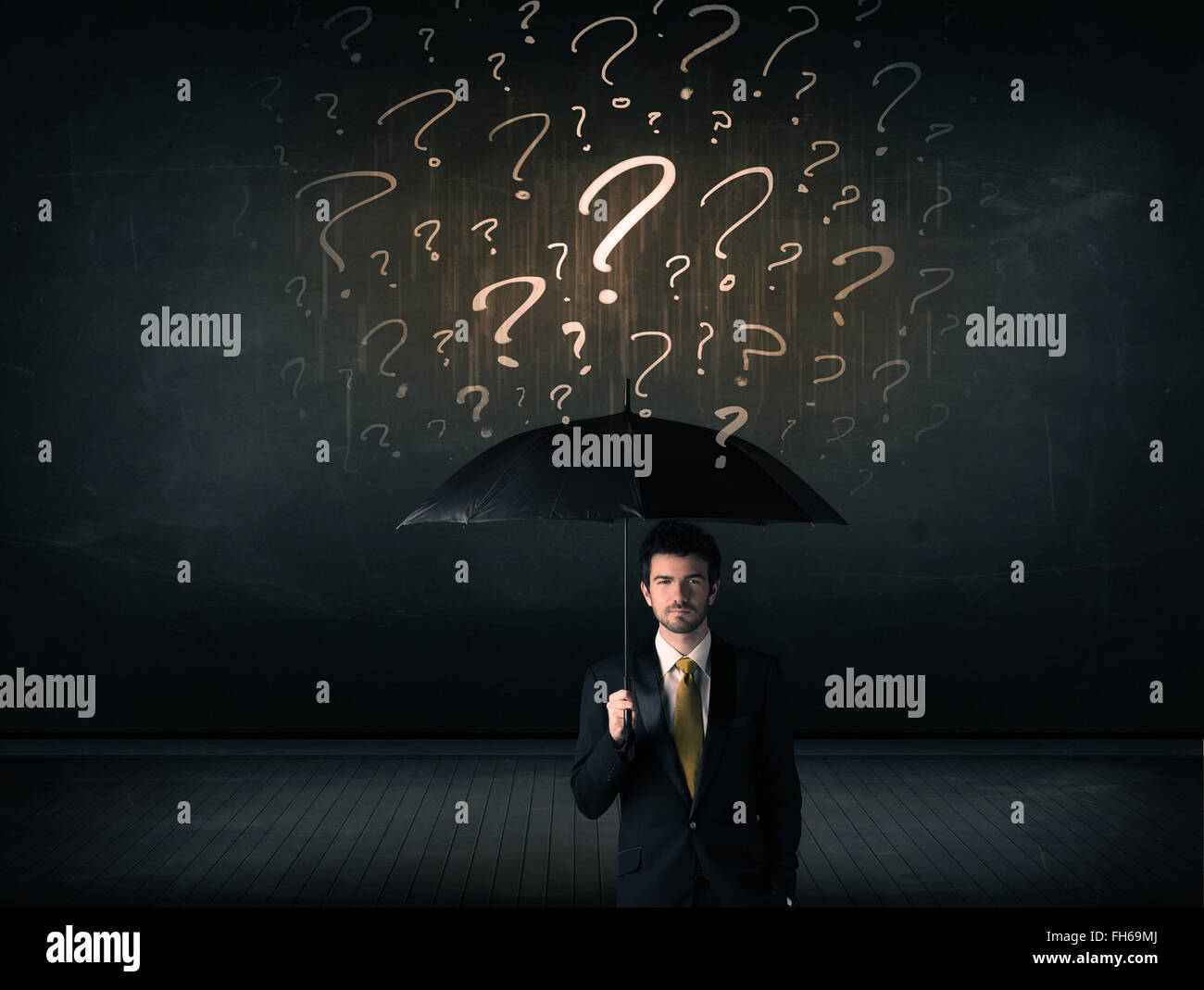 Businessman with umbrella and a lot of drawn question marks Stock Photo