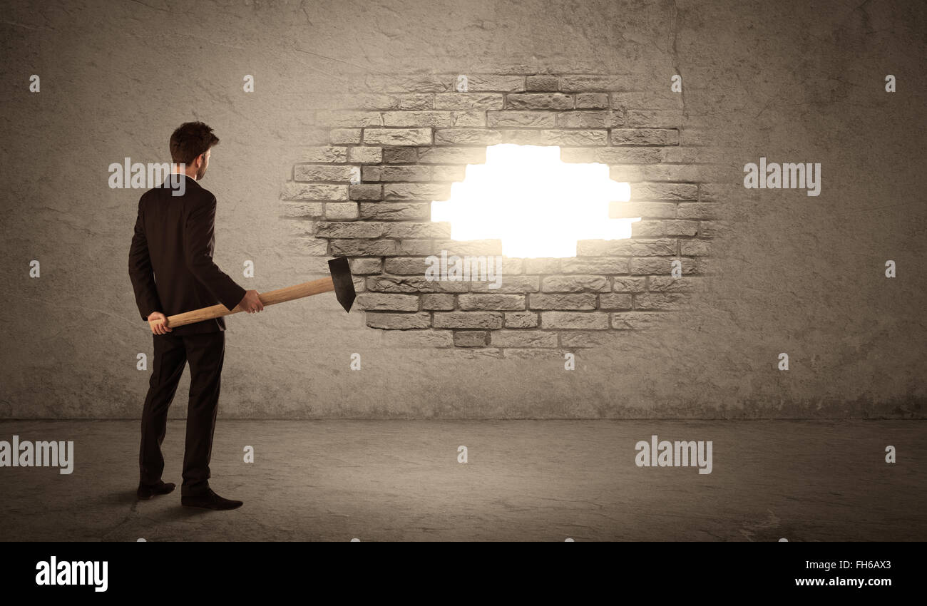 Business man hitting brick wall with hammer and opening a hole Stock