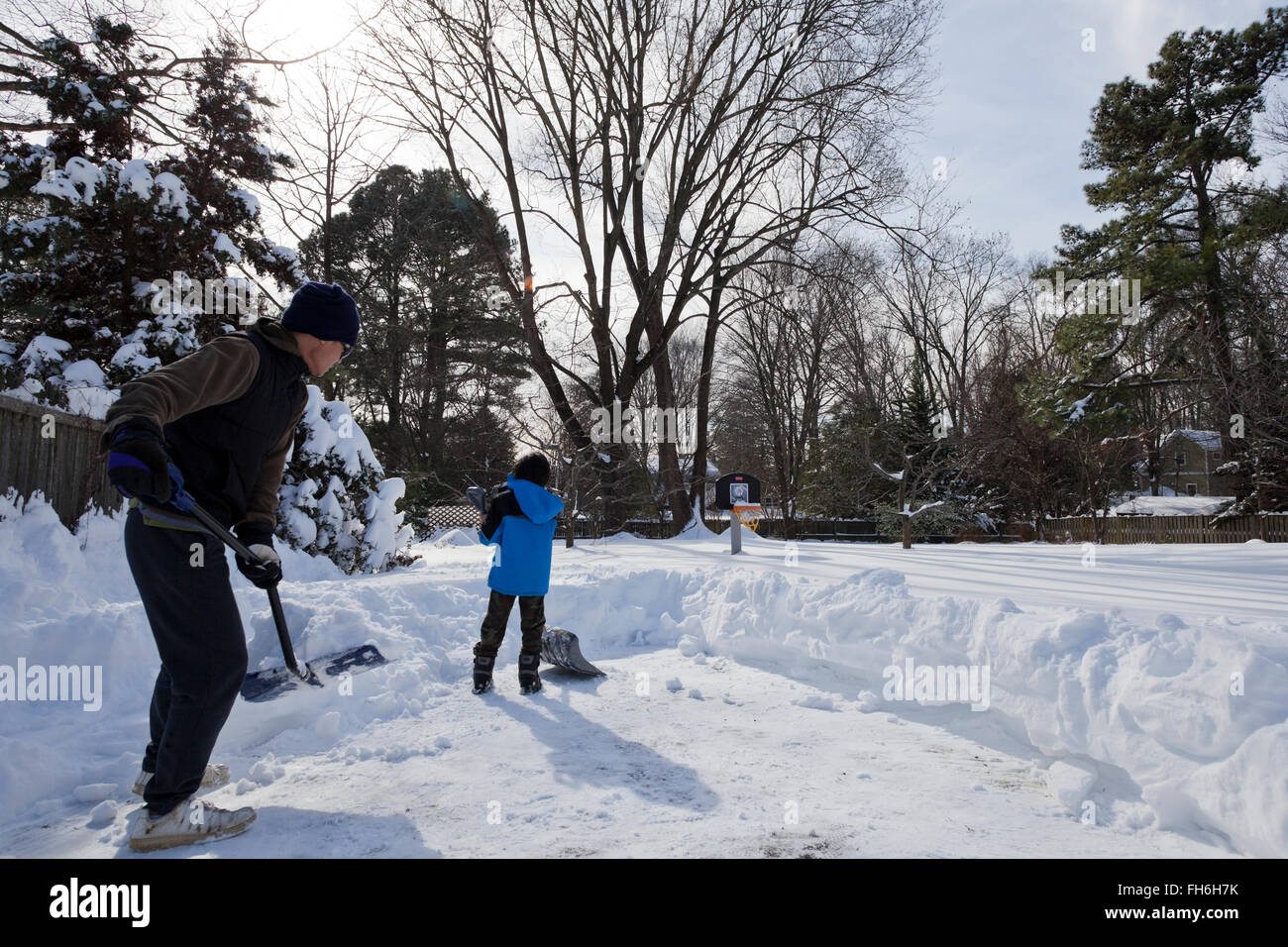 Man and child shoveling snow from driveway - Virginia USA Stock Photo