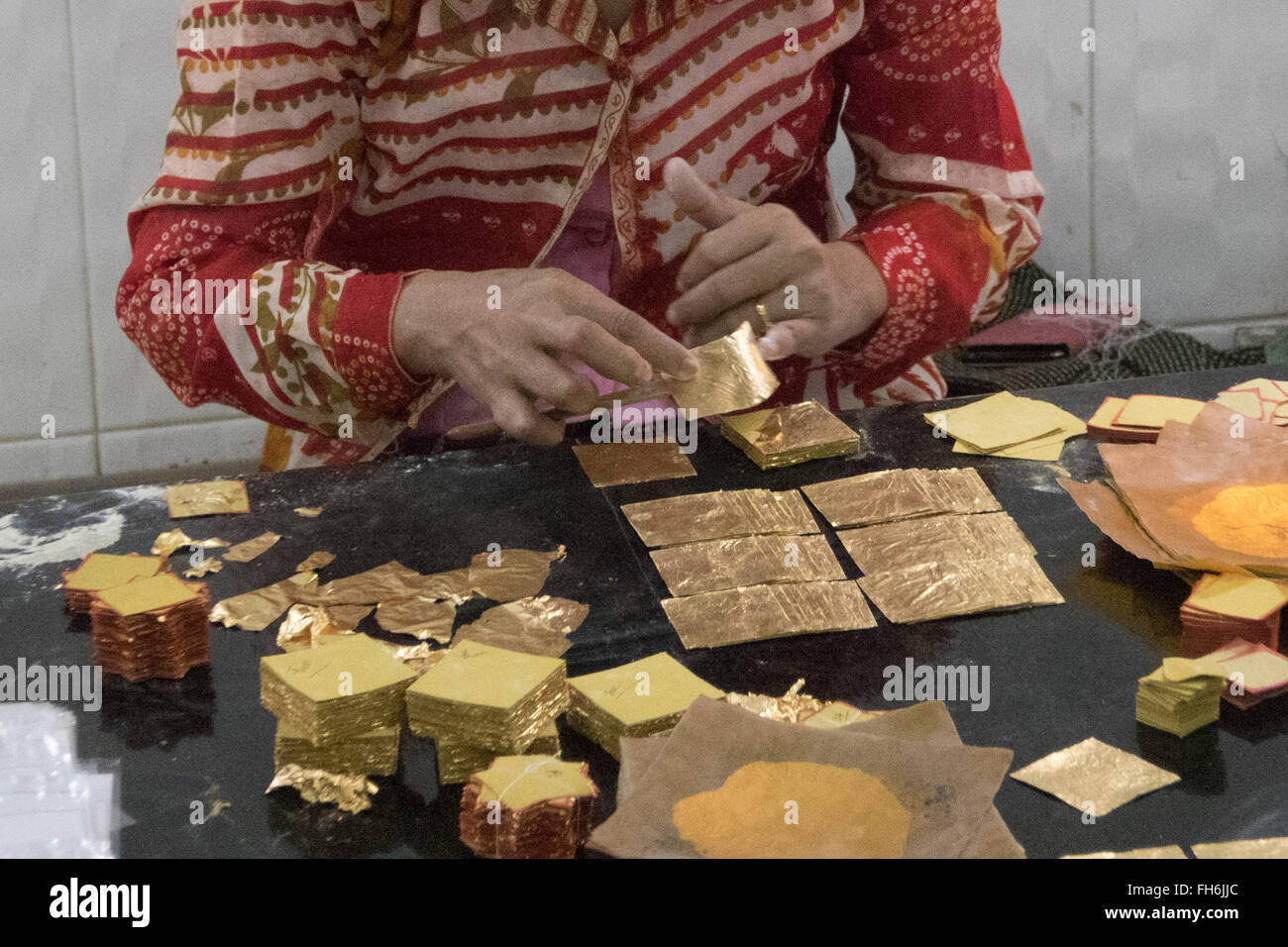 Packaging individual pieces of gold leaf for sale  Mandalay,Myanmar Stock Photo