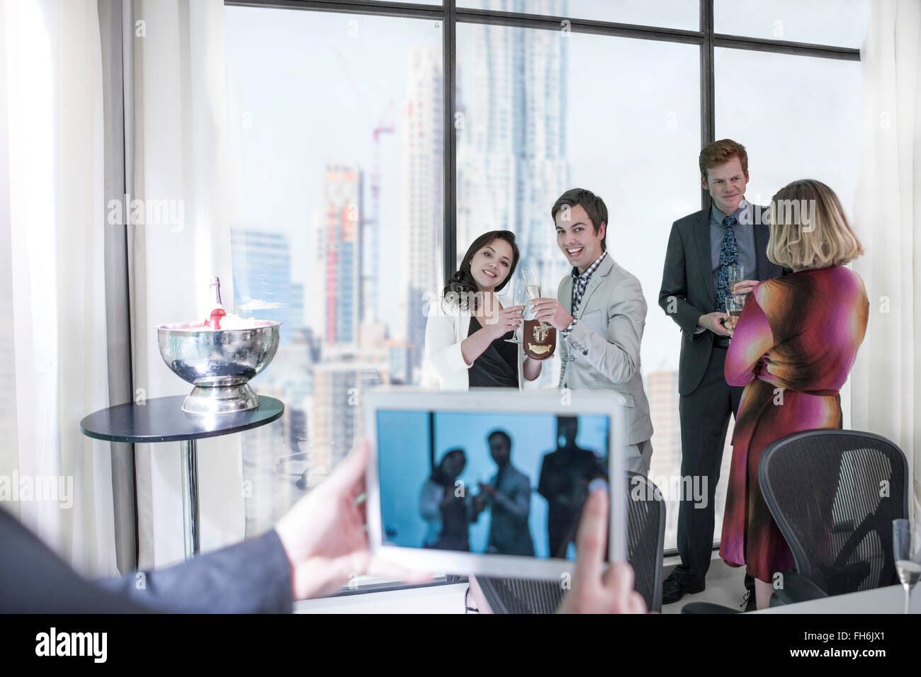 Successful business people having a work party, man taking picture with digital tablet Stock Photo