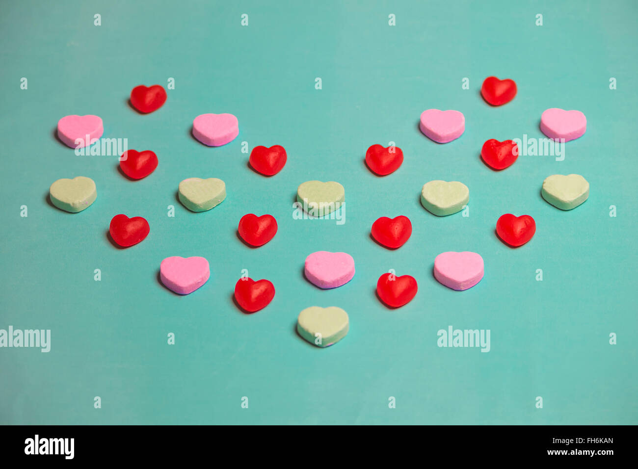 Valentine's Day Red Gummy and Conversation Hearts on Green Background