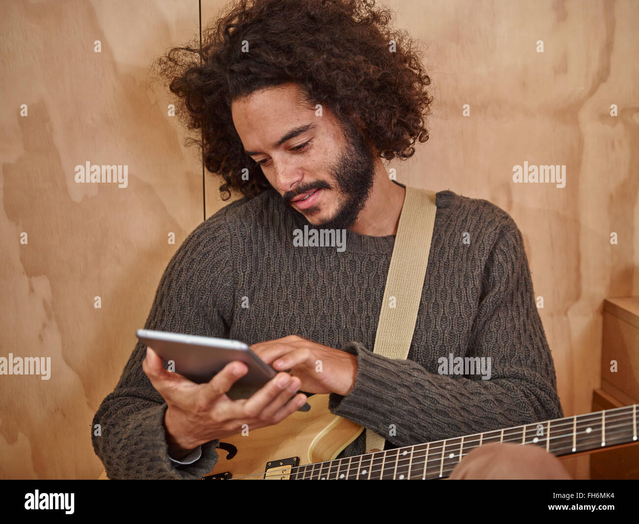 Young man with electric guitar looking at digital tablet Stock Photo