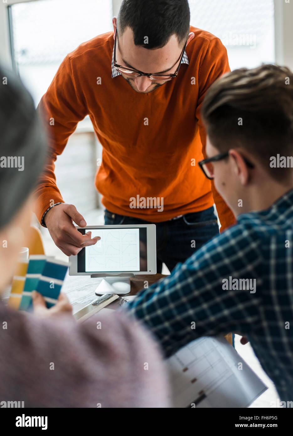 Colleagues in office looking at digital tablet showing different shapes Stock Photo