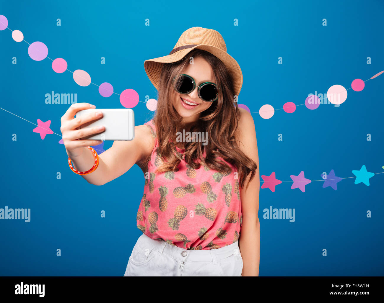Smiling pretty young woman taking selfie using smartphone over blue ...