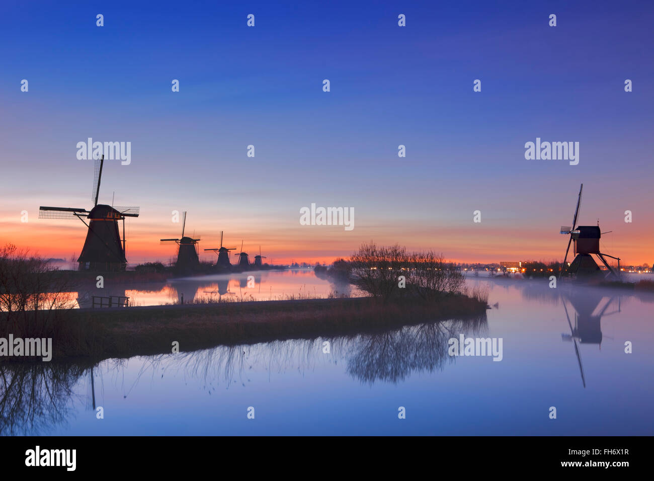Traditional Dutch windmills with ground fog just before sunrise. Photographed at the famous Kinderdijk. Stock Photo