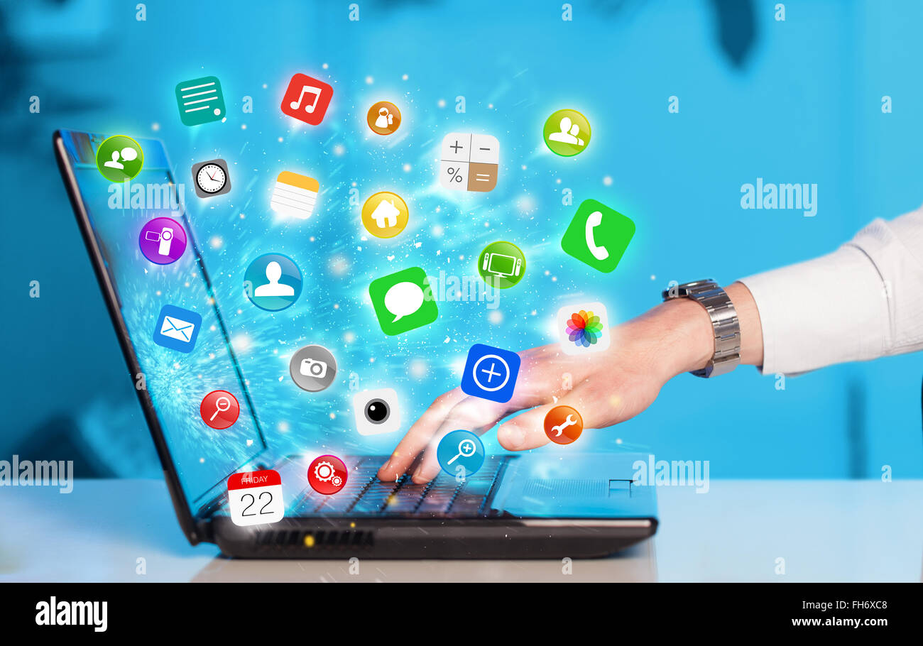 Hand pressing modern laptop with mobile app icons and symbols Stock Photo