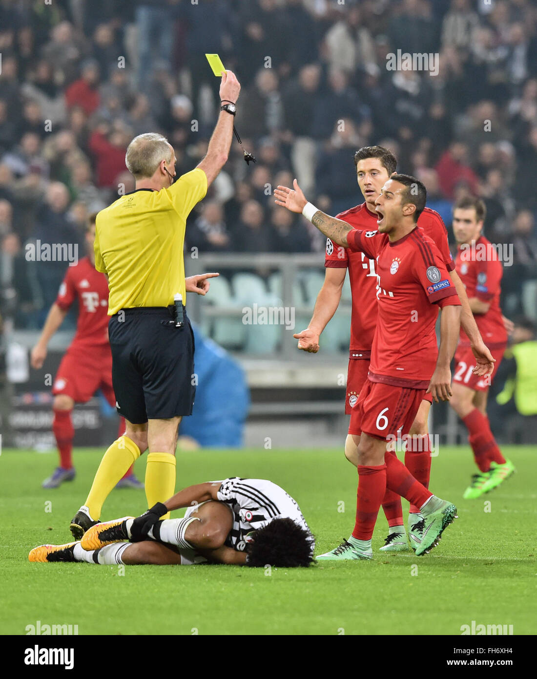 Referee Martin Atkinson from England shows the yellow card to Munich's  Robert Lewandowski (2nd R) while Juve's Juan Cuadrado lies on the ground  during the UEFA Champions League round of 16 first