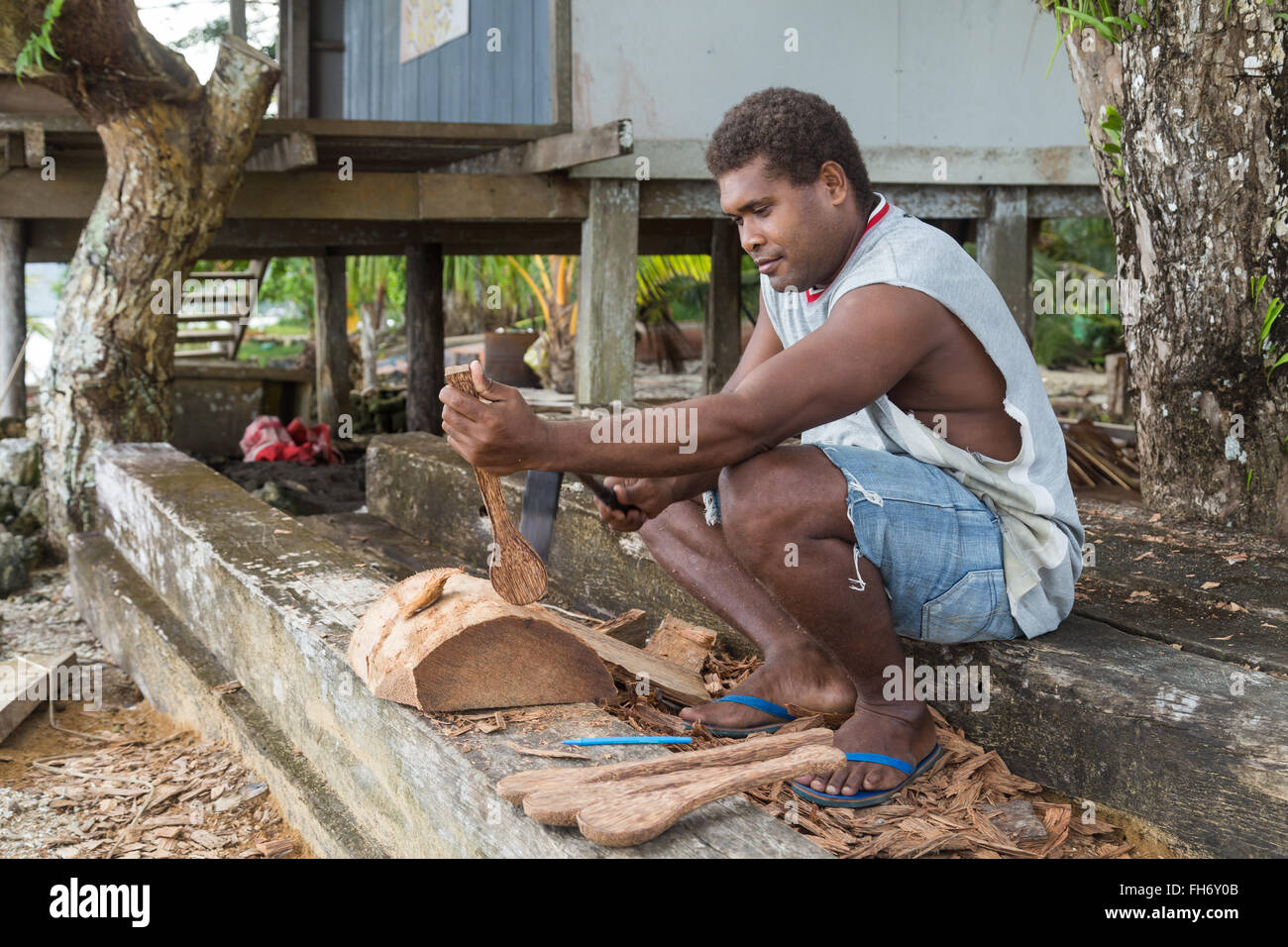 Chea Village, Solomon Islands - June 15, 2015: A man is woodcarving a spoon. Wood carving is typical for the Marovo Lagoon. Stock Photo