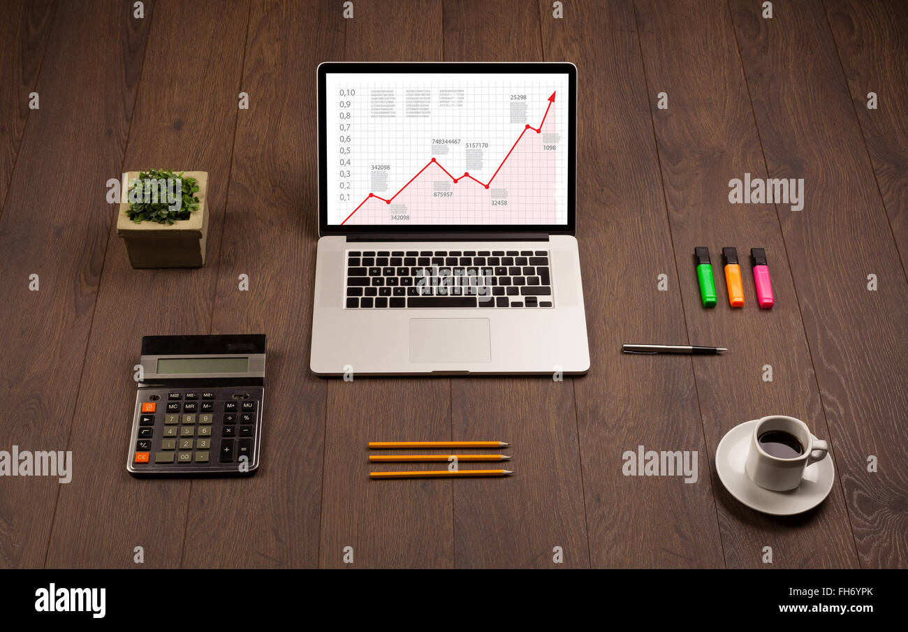 Computer desk with laptop and red arrow chart in screen Stock Photo - Alamy
