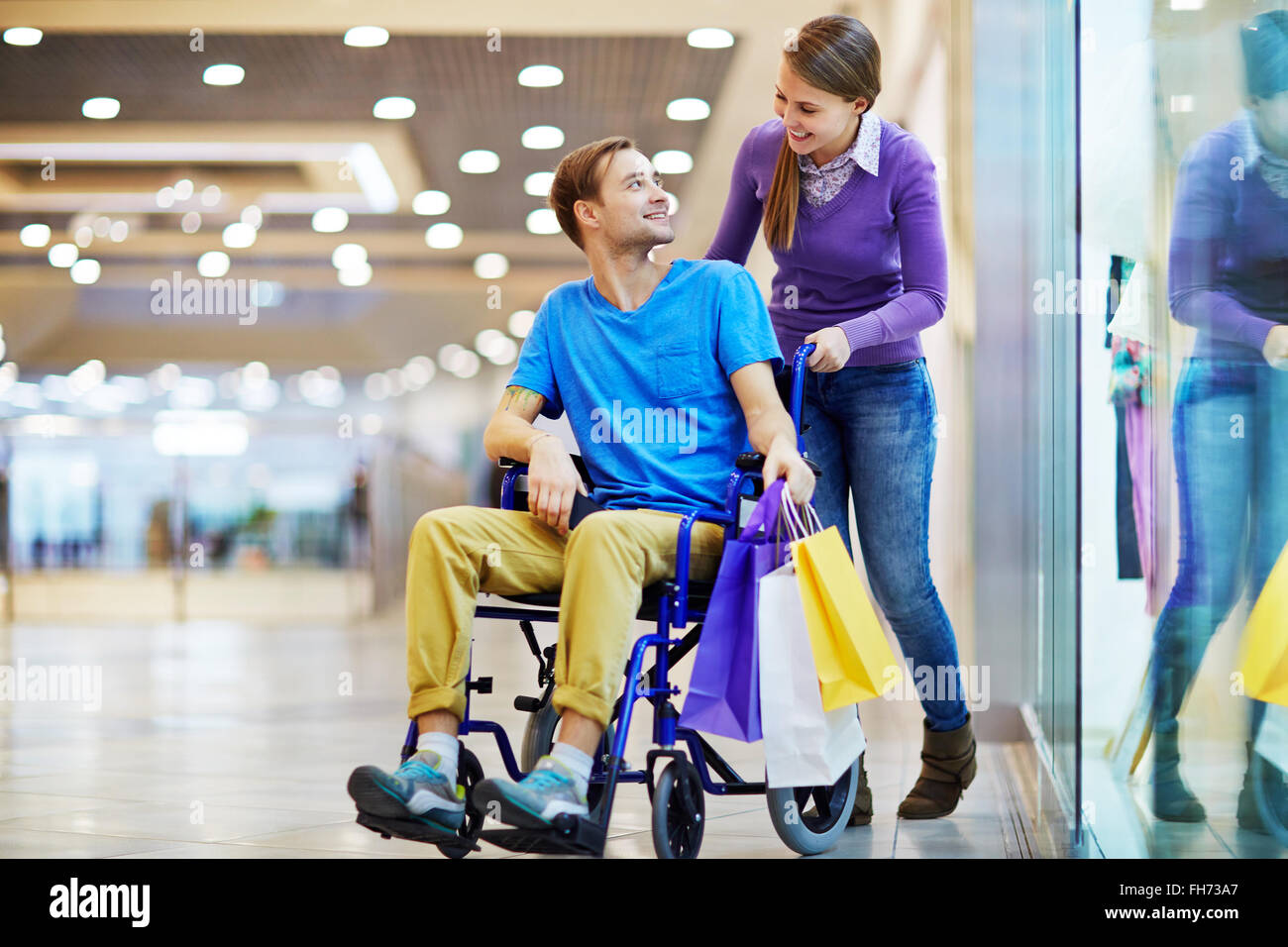 Caring girl talking to her boyfriend in wheelchair during sale Stock Photo