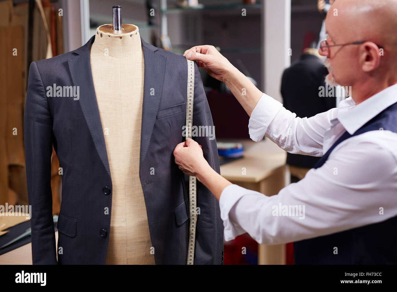 Mature tailor taking measures of man jacket on mannequin Stock Photo ...