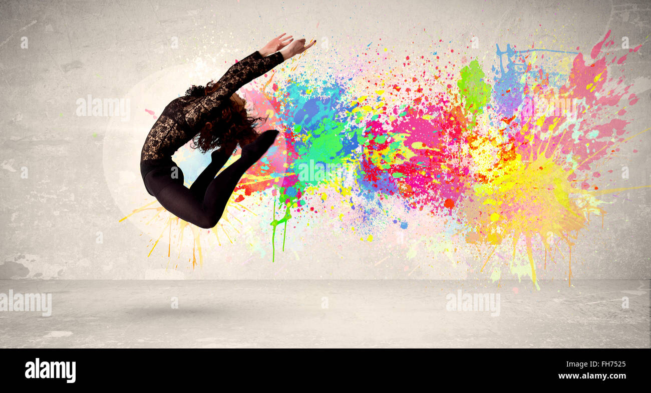 Happy teenager jumping with colorful ink splatter on urban background Stock Photo