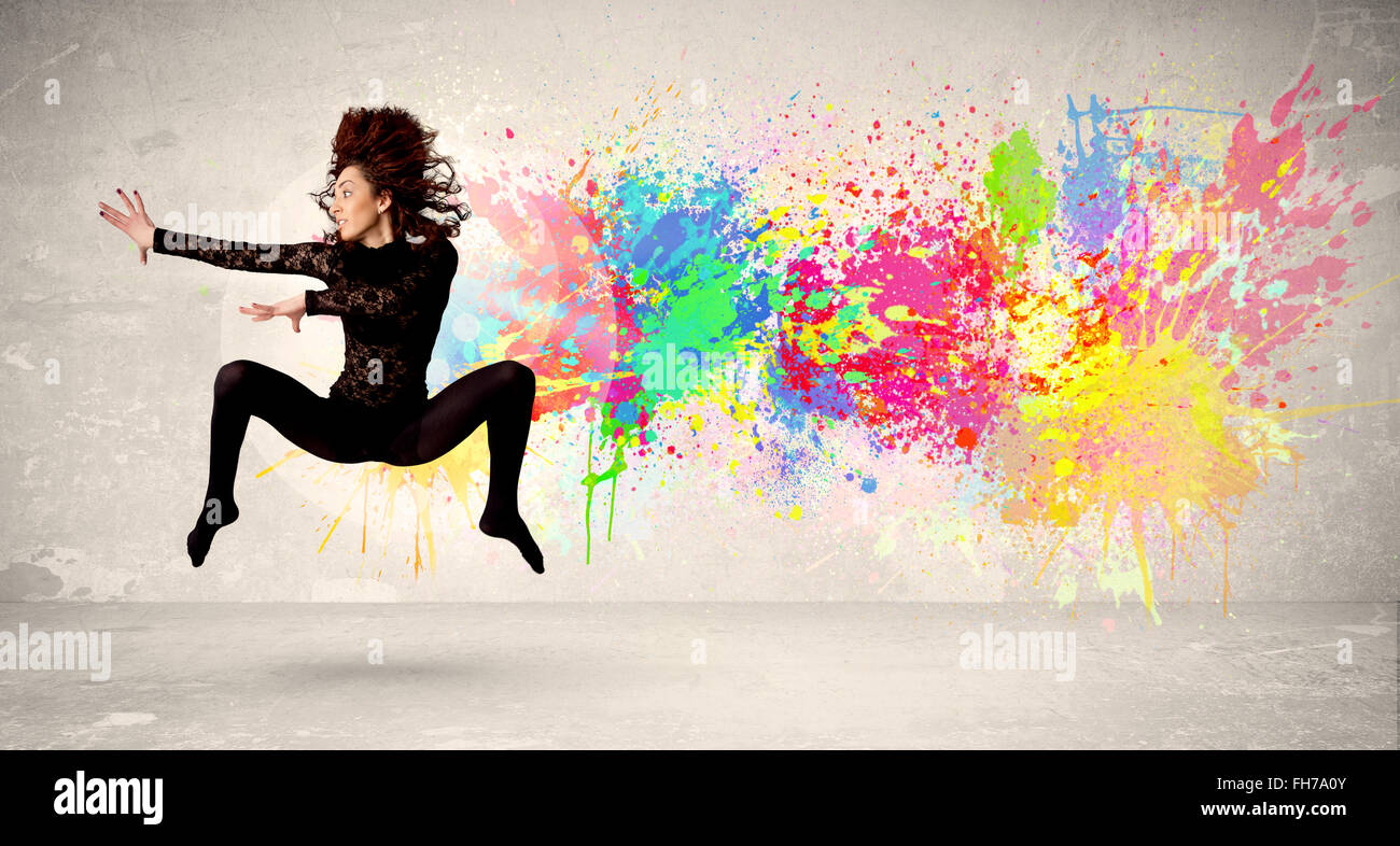 Happy teenager jumping with colorful ink splatter on urban background Stock Photo