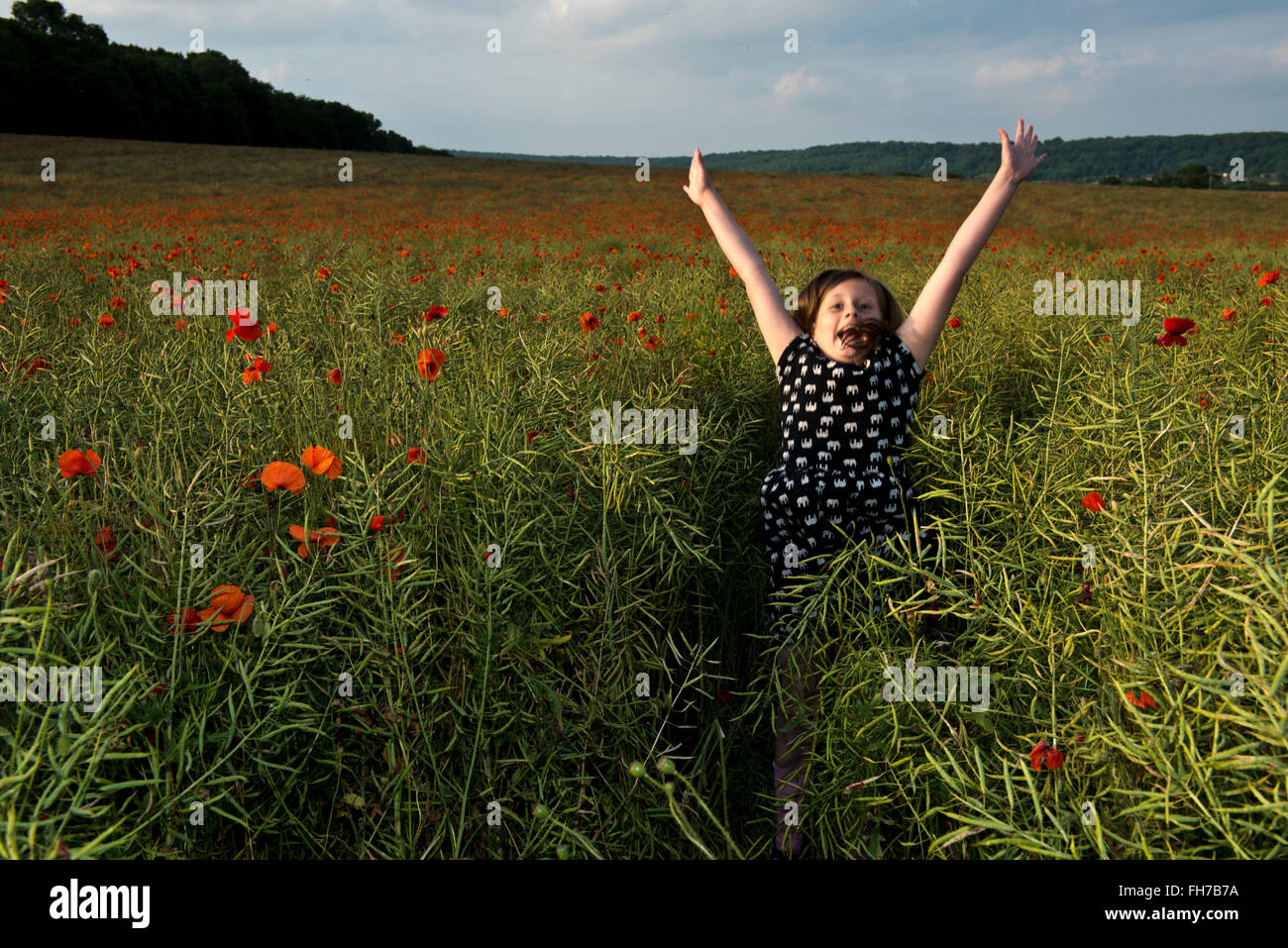 Model released image of a young girl jumping in a poppy field, near Tring, Hertfordshire, UK Stock Photo