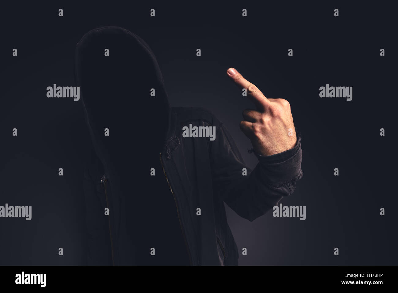 Middle finger offensive hand gesture given by unrecognizable hooded person. Stock Photo