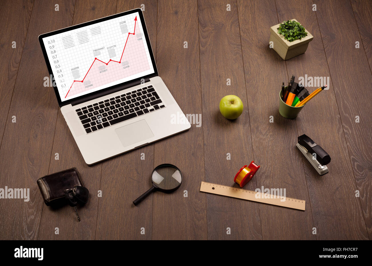 Computer desk with laptop and red arrow chart in screen Stock Photo - Alamy