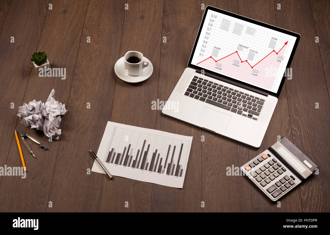 Computer desk with laptop and red arrow chart in screen Stock Photo - Alamy