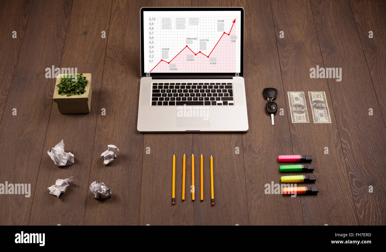 Computer desk with laptop and red arrow chart in screen Stock Photo - Alamy
