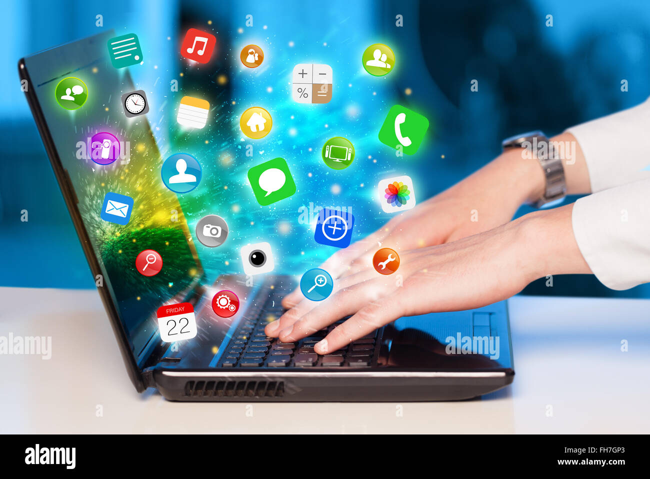 Hand pressing modern laptop with mobile app icons and symbols Stock Photo