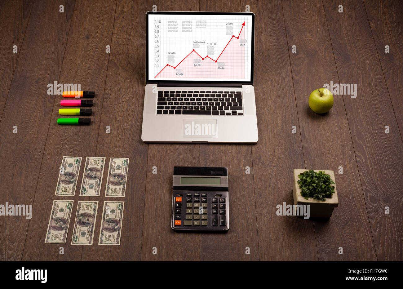 Computer desk with laptop and red arrow chart in screen Stock Photo
