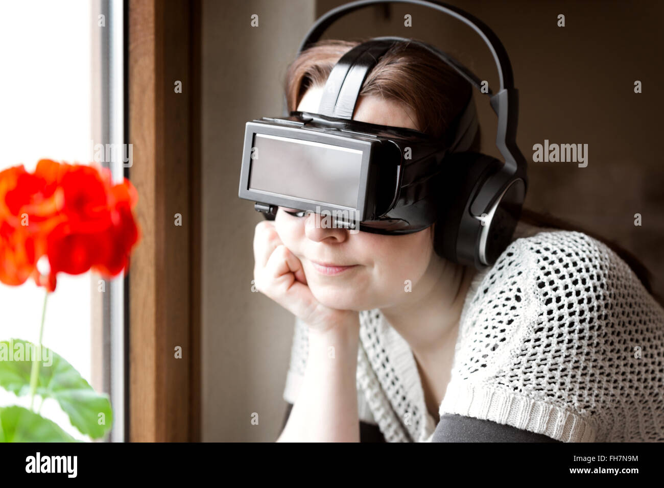 woman is wearing vr glasses, leaning at a window Stock Photo
