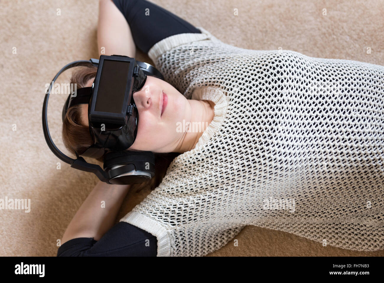 downview of a woman, wearing vr glasses, laying on the ground Stock Photo