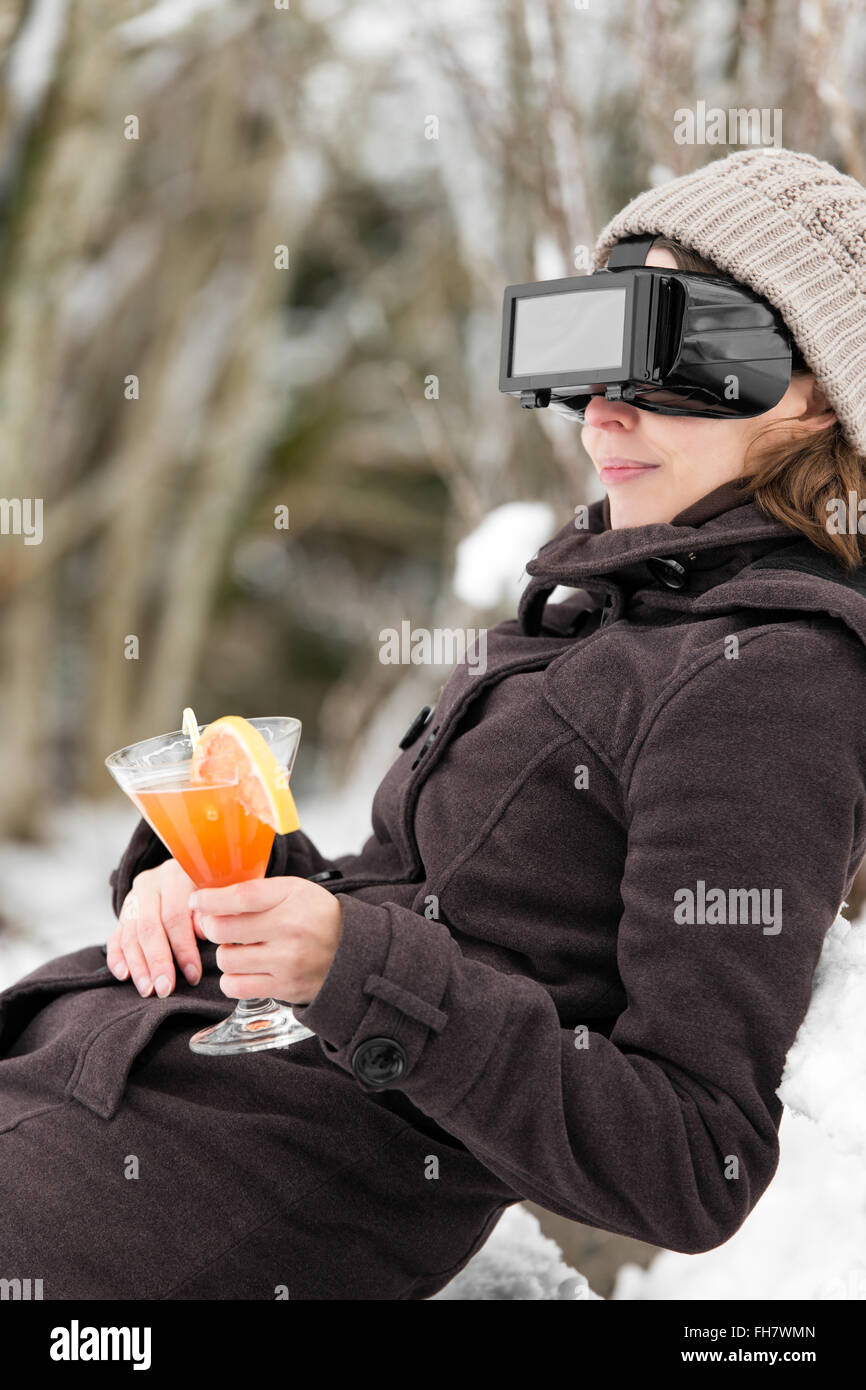 woman in snow is wearing virtual reality glasses and dreaming of summer Stock Photo