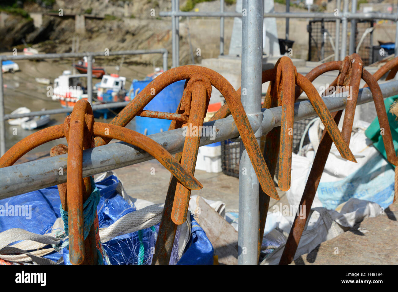 Rusty anchors hanging from railing in Newquay harbour, Cornwall