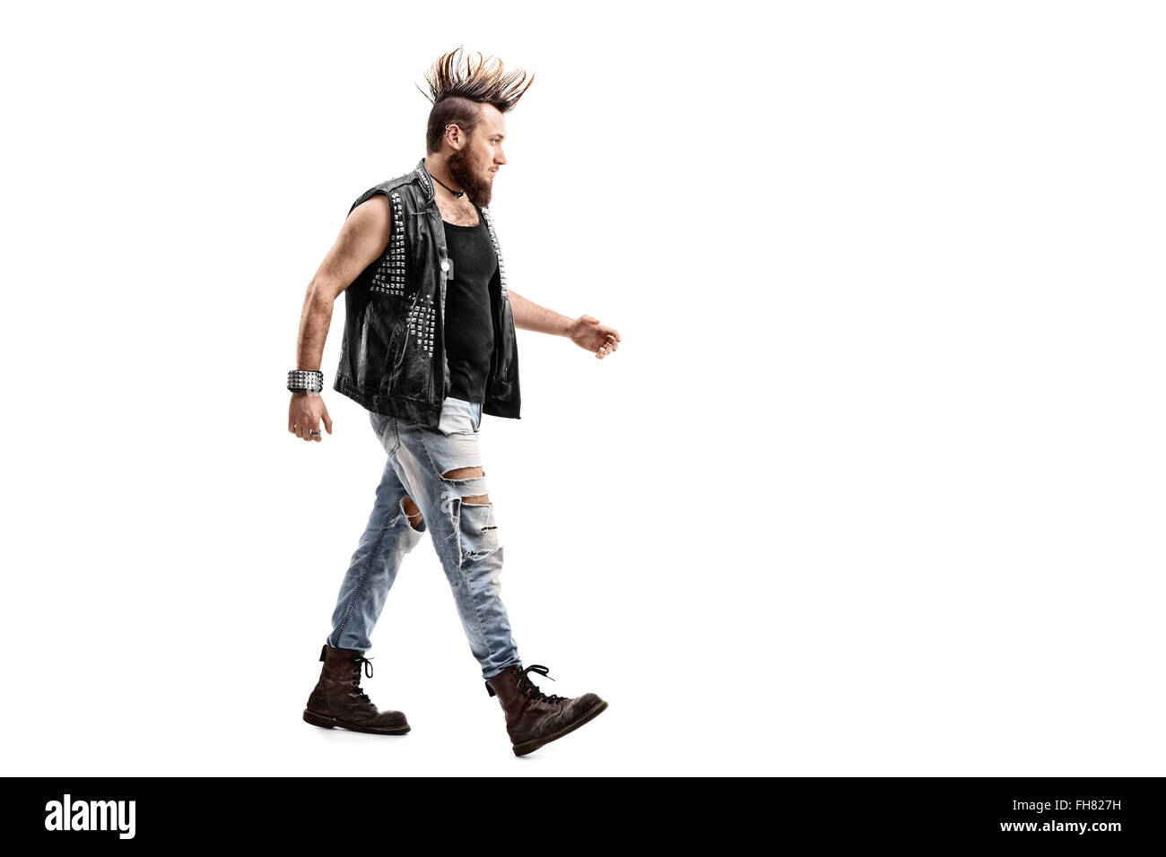 Full length profile shot of an angry male punk rocker walking isolated on white background Stock Photo