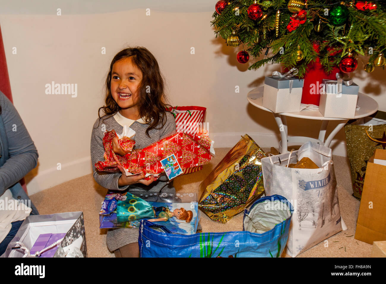 A Mixed Race Child Opening Her Christmas Presents On Christmas Day, Brighton, Sussex, UK Stock Photo