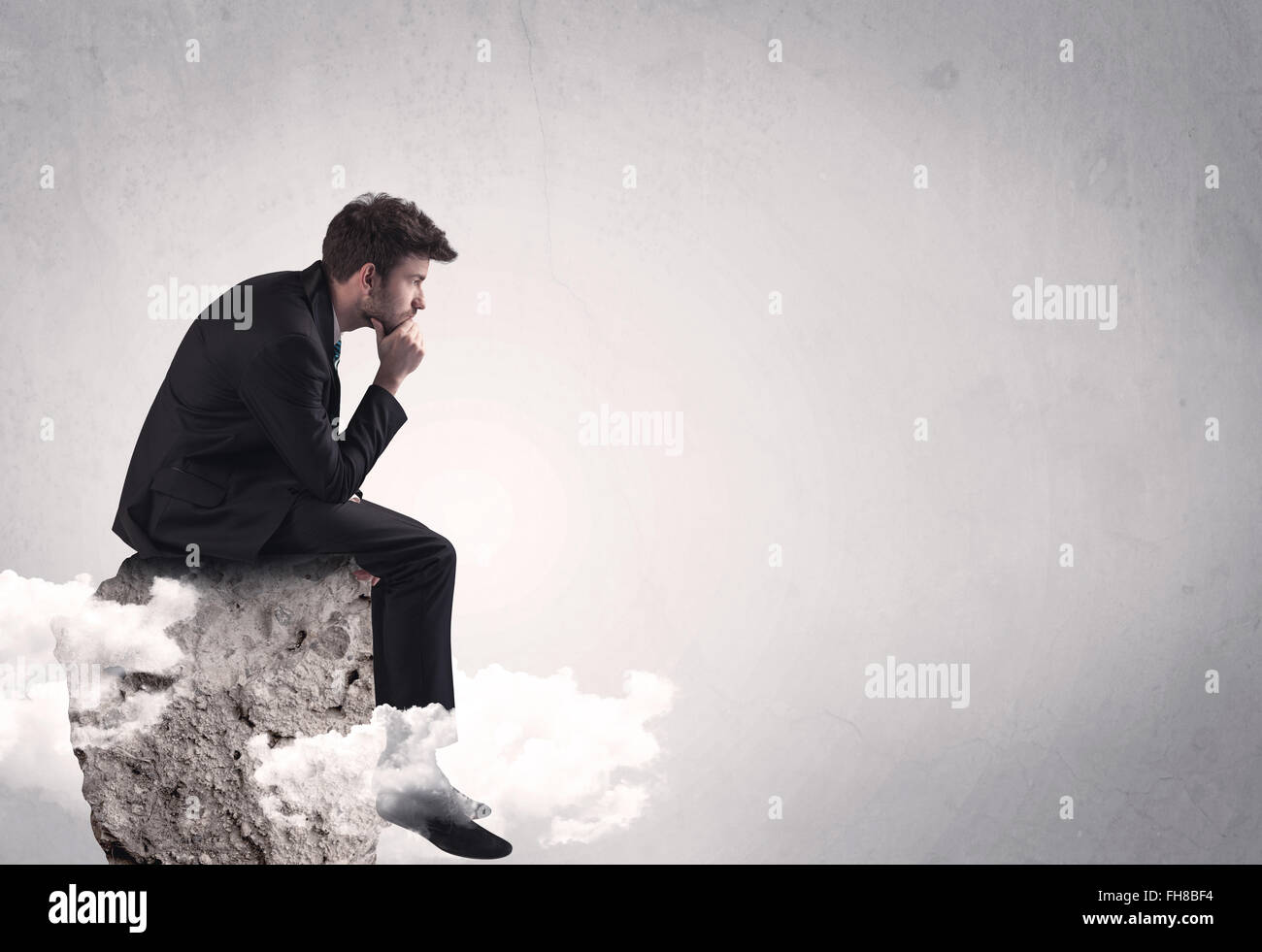 Office worker sitting on top of a rock Stock Photo