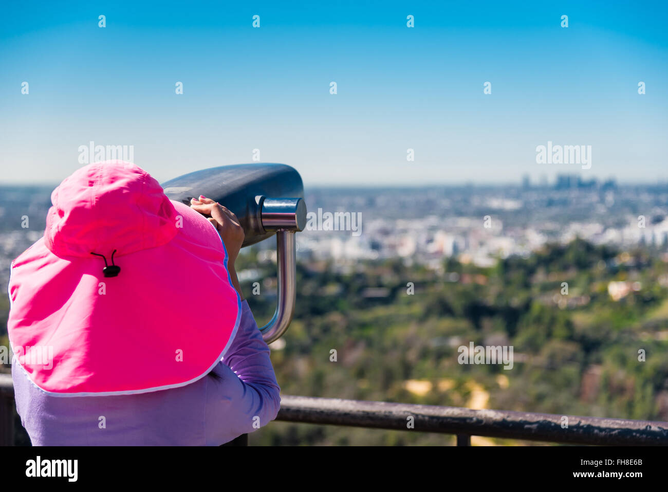 girl using coin operated binoculars to watch LA skyline Stock Photo