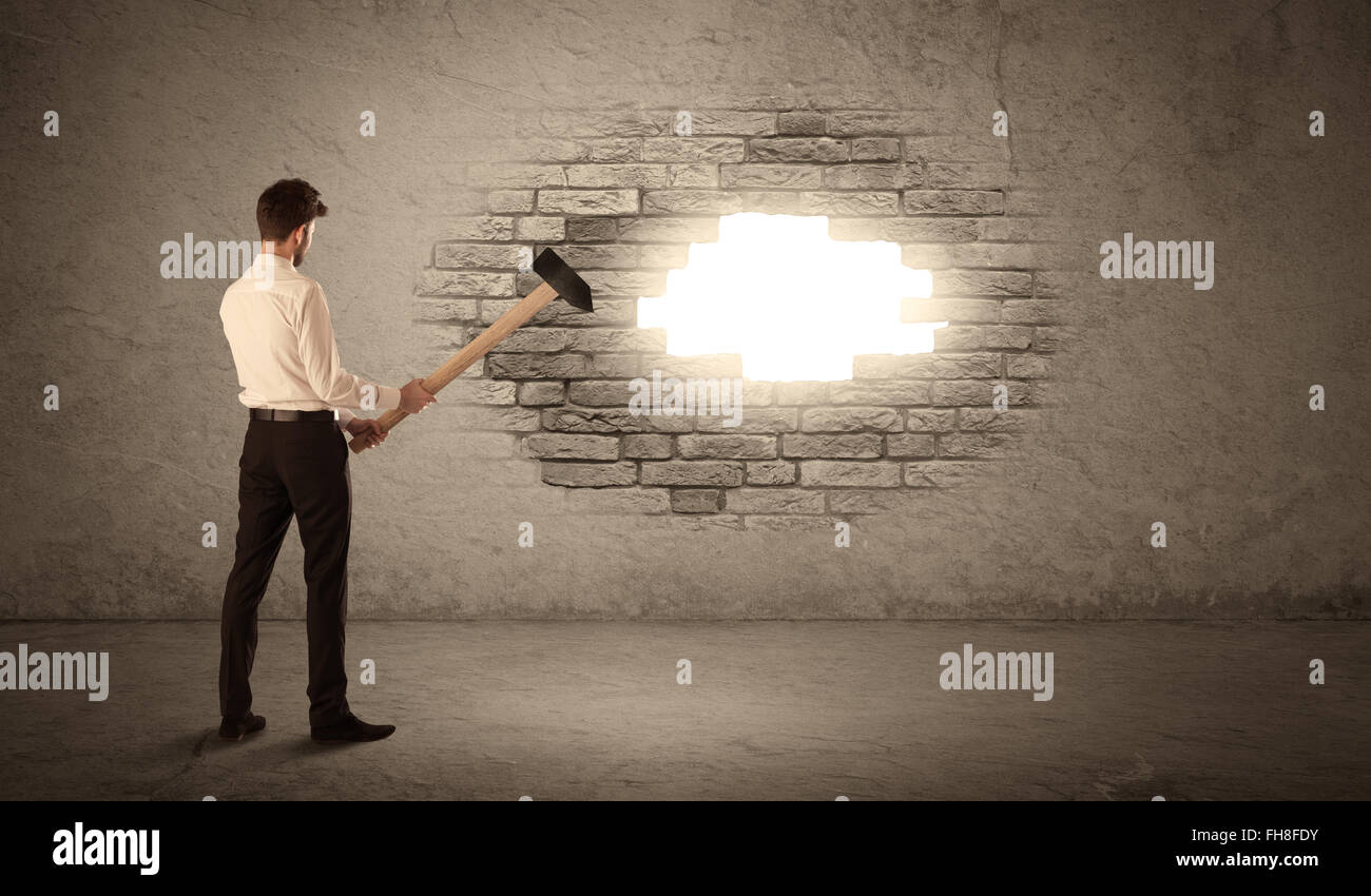 Business man hitting brick wall with hammer and opening a hole Stock