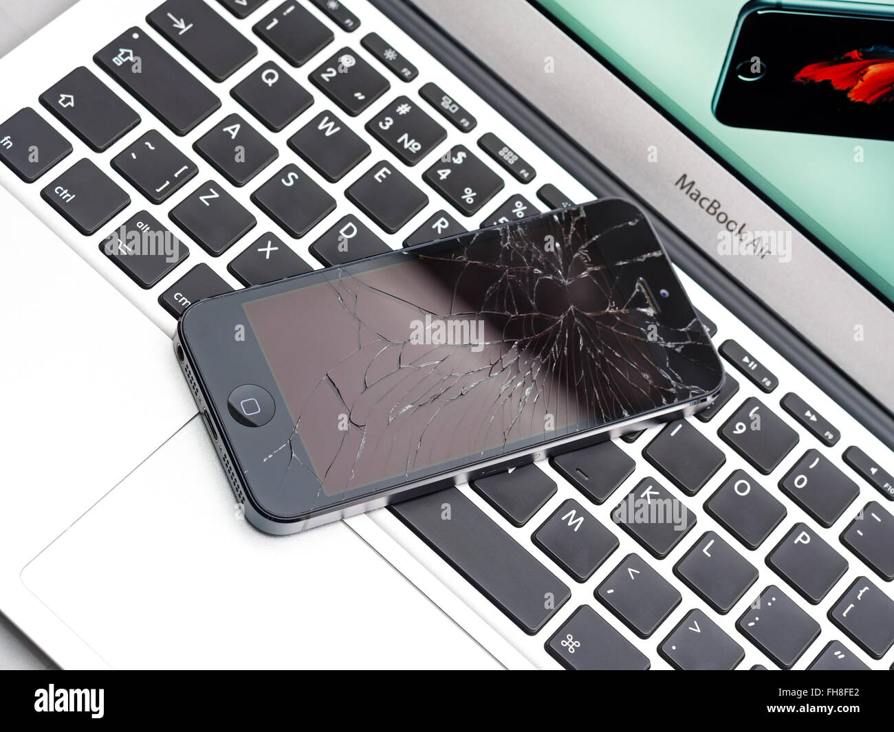 Los Angeles, CA, USA - December 07, 2015: Broken Apple iPhone with cracked screen on Apple MacBook Air laptop Stock Photo