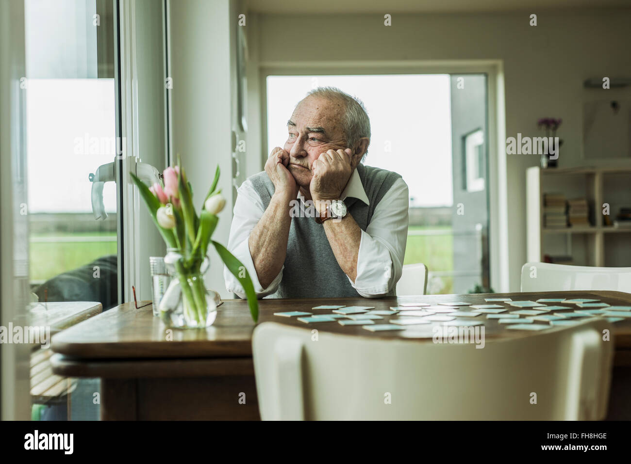 Portrait of sad senior man looking through window Stock Photo
