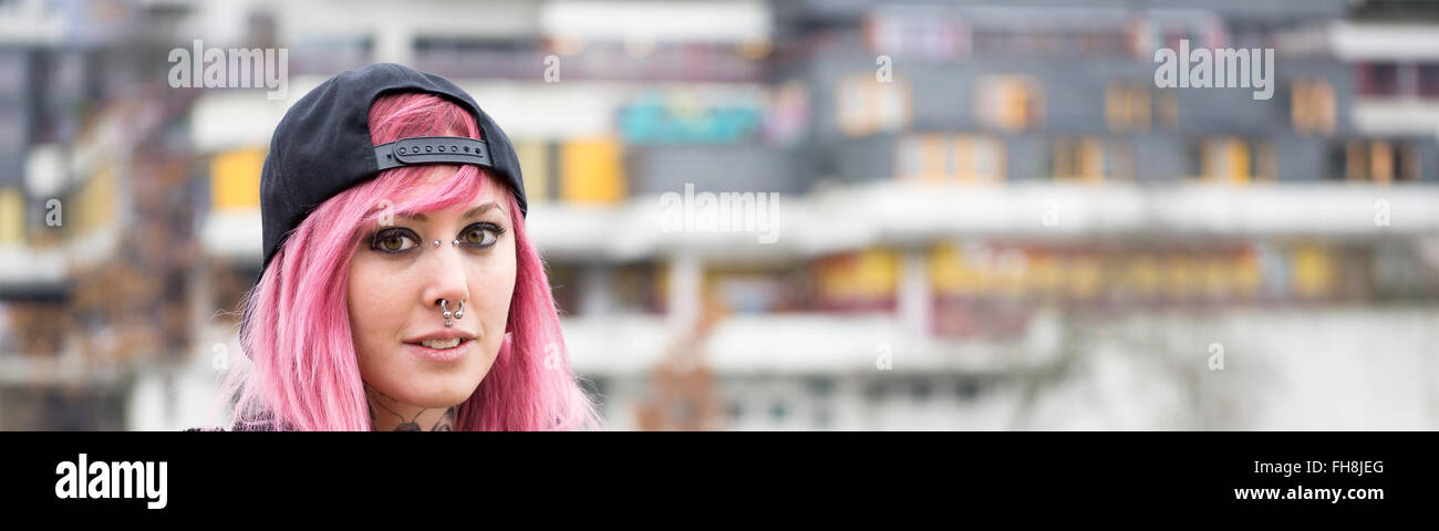 woman with piercings and pink hair at housing estate Stock Photo