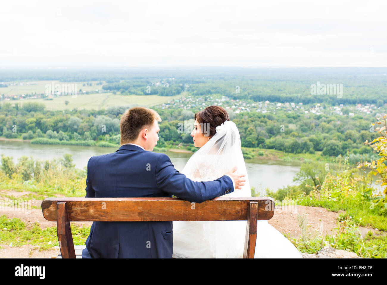 Romantic wedding couple sitting on a bench in the park Stock Photo - Alamy