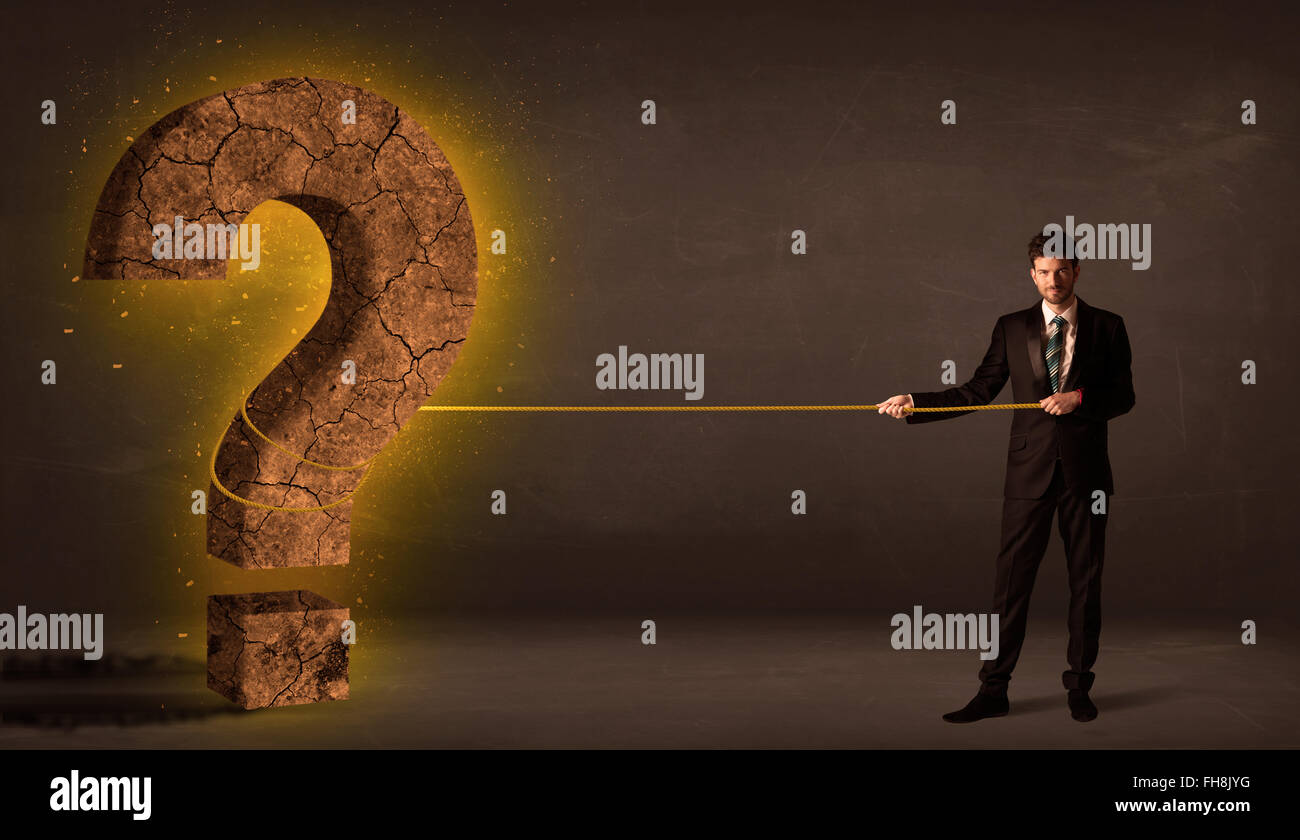 Business man pulling a big solid question mark stone Stock Photo