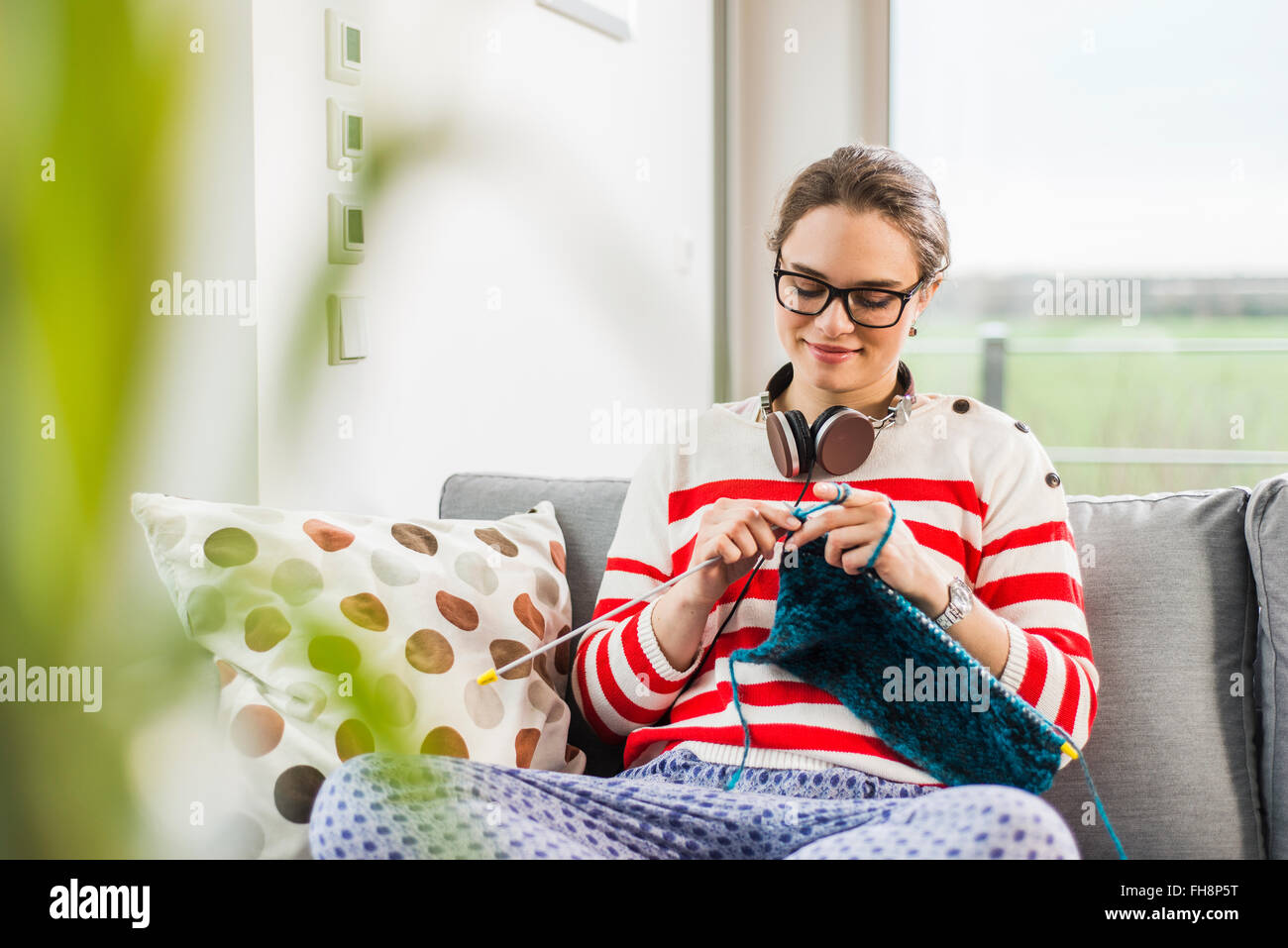 Young woman sitting on couch knitting Stock Photo - Alamy