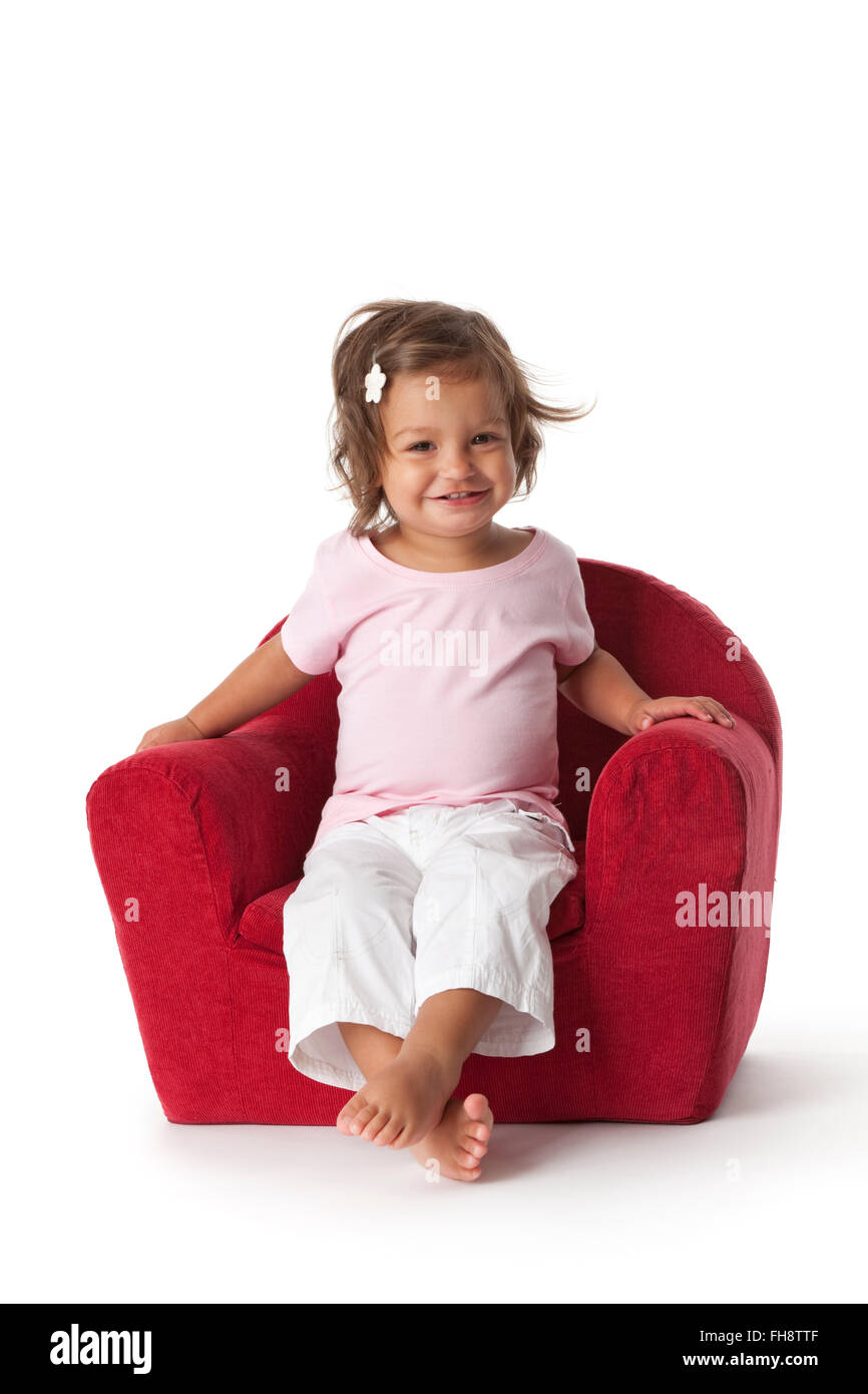 Toddler girl making fun in an armchair on white background Stock Photo