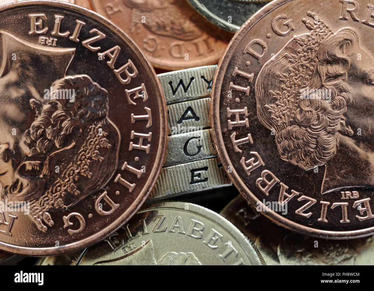 ONE POUND COINS EDGE LETTERS READING THE WORD 'WAGE'  WITH COINS RE THE NATIONAL LIVING WAGE WAGES INCOMES WORKERS JOB JOBS UK Stock Photo