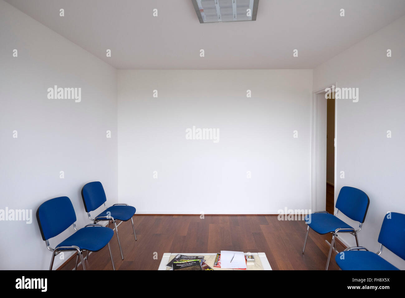Empty doctor waiting room with white walls and blue chairs Stock Photo