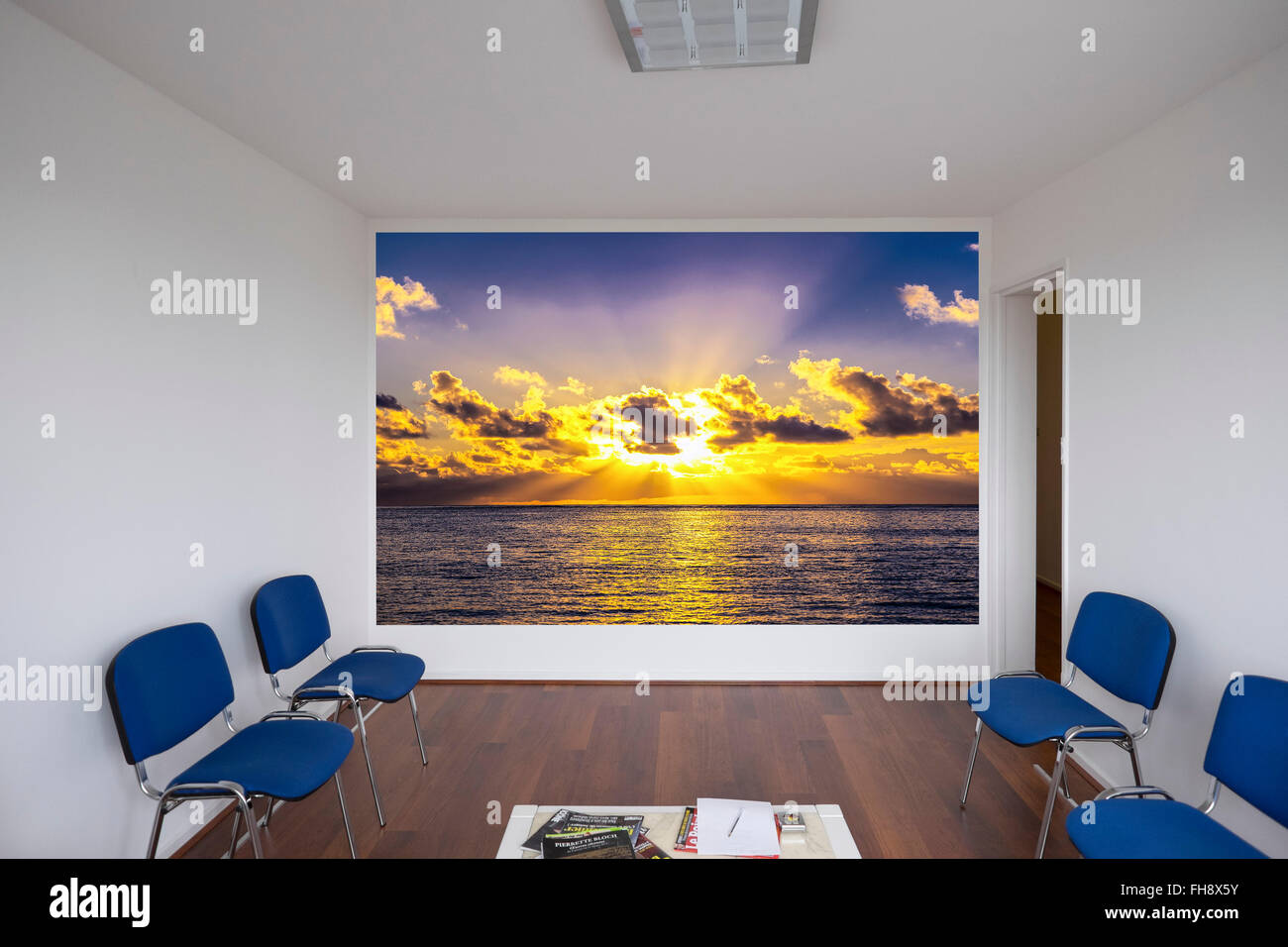 Empty doctor waiting room with blue chairs and sunset poster, France, Europe Stock Photo